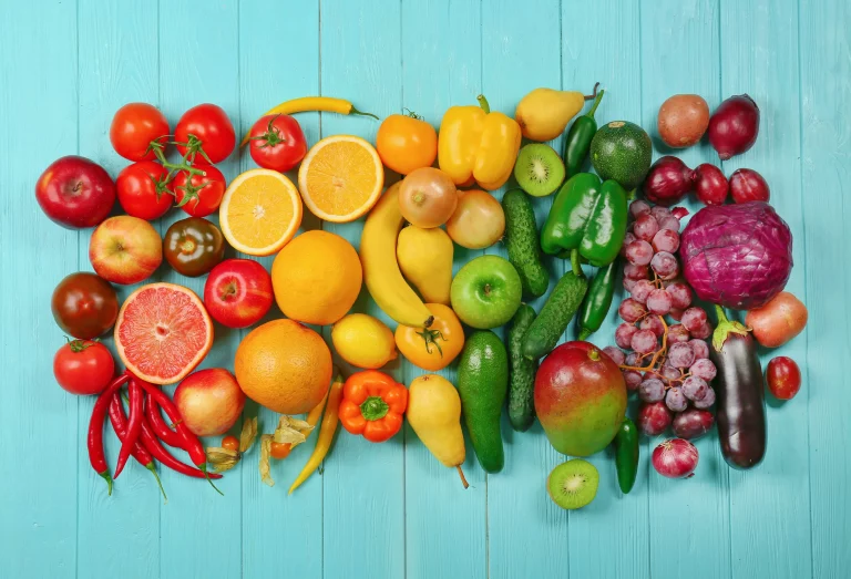 A flat lay of colorful fruits and vegetables arranged in a rainbow pattern.