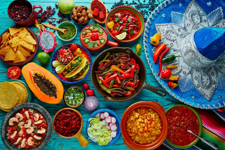 Colorful bowls full of Mexican food on a turquoise wooden table.