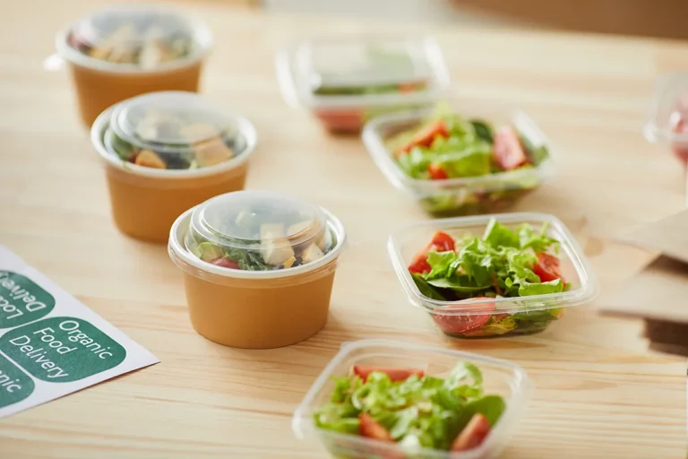 Prepackaged salads in plastic containers on a countertop ready to be labeled for sale.