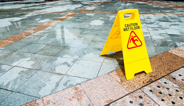 A yellow wet floor caution sign on a concrete tile floor.