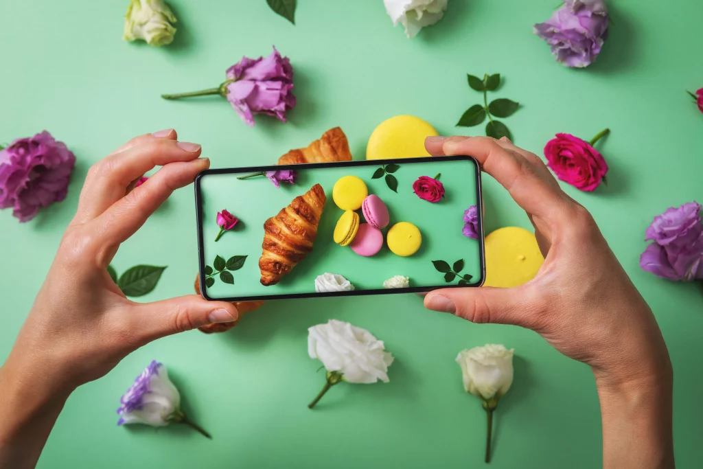 A baker taking a photo of Macarons on a green background