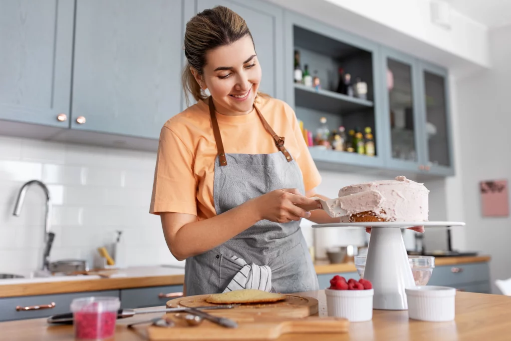 A home baker decorating a cake on a pedestal.