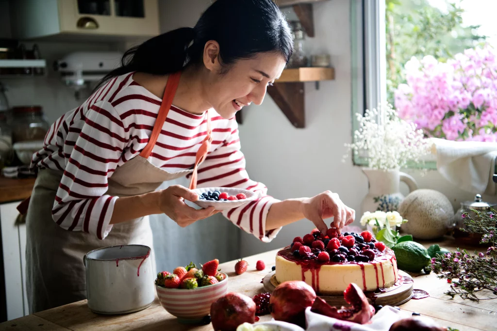 A baker organizing fruit on a cake