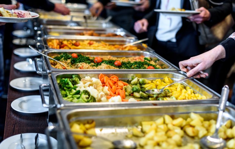 Various cooked vegetables in chafing dishes at a catered event.