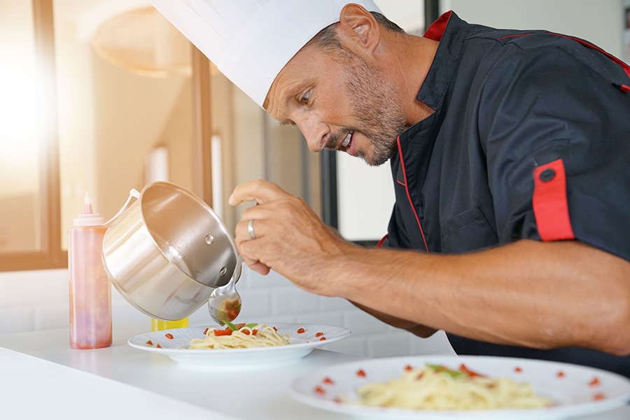 A private chef in a home kitchen preparing a pasta dish.