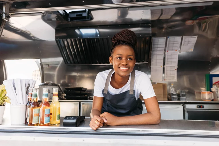 A young mobile food business owner standing in the service window of her food truck waiting for customers.