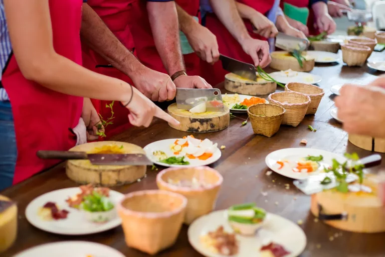 A group of students in a cooking class preparing traditional Thai food on a wooden table.